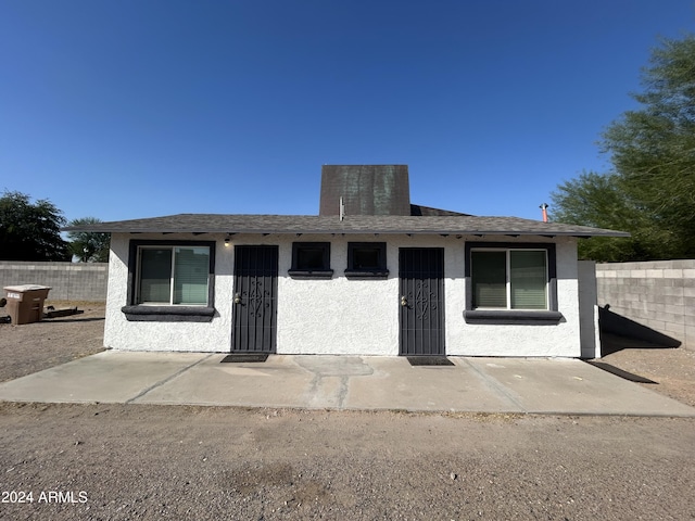 bungalow-style home featuring fence, roof with shingles, and stucco siding