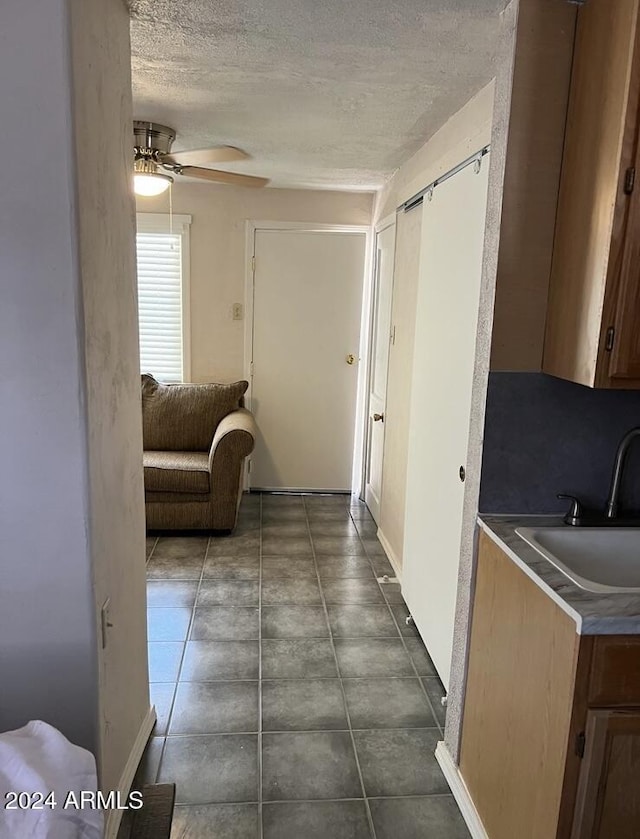 hall with a textured ceiling, baseboards, and a sink