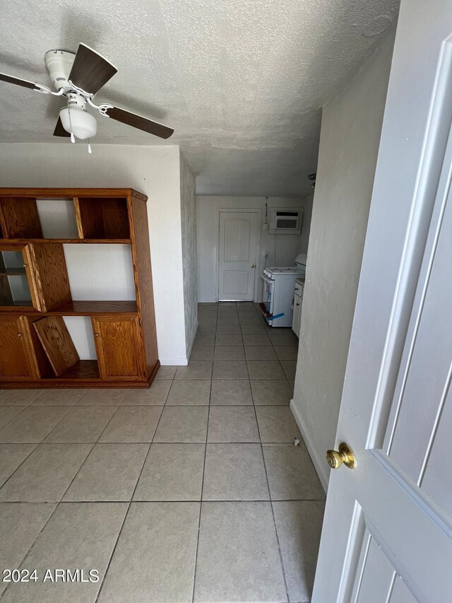 hall featuring a wall mounted AC, a textured ceiling, and light tile patterned floors