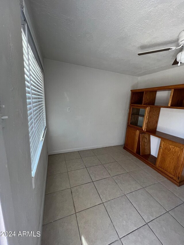 unfurnished room with a ceiling fan, a textured ceiling, and light tile patterned floors