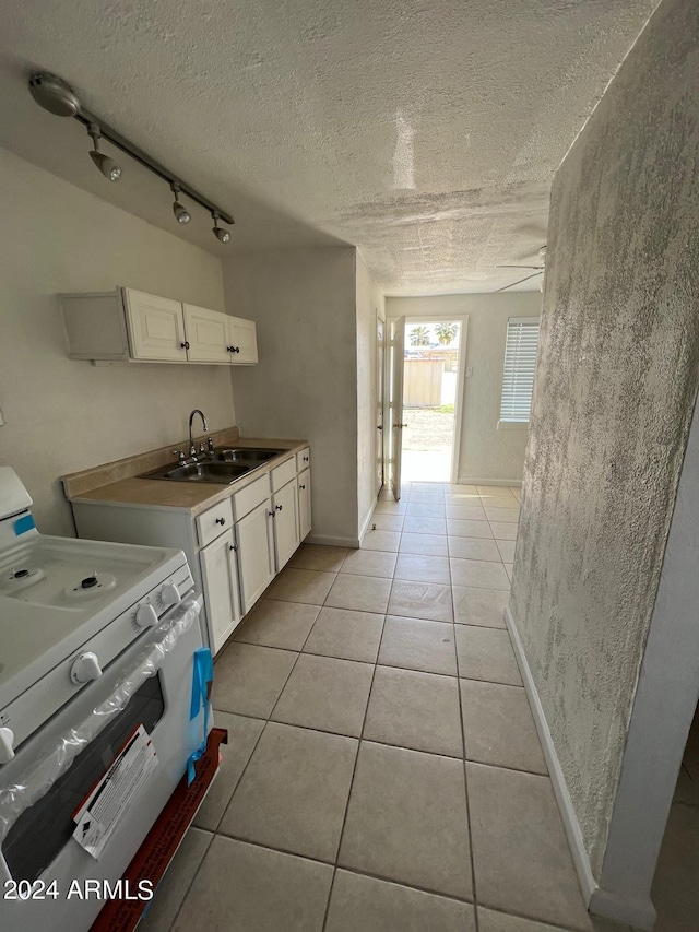 kitchen with a textured ceiling, a sink, white cabinetry, stove, and light tile patterned floors