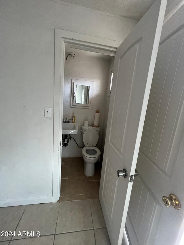 bathroom featuring sink, toilet, a textured ceiling, and tile patterned floors