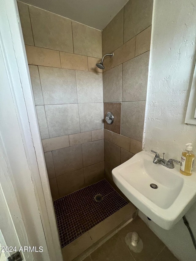 bathroom with tile patterned flooring, sink, and tiled shower