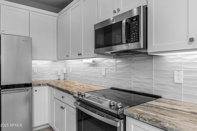 kitchen featuring light stone countertops, white cabinetry, appliances with stainless steel finishes, and tasteful backsplash