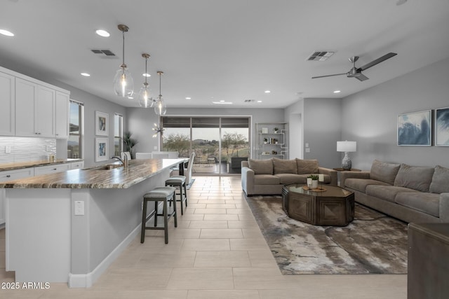 living room featuring sink, ceiling fan, and light tile patterned flooring