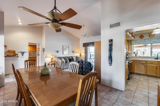 dining room with ceiling fan, sink, light tile patterned floors, and high vaulted ceiling