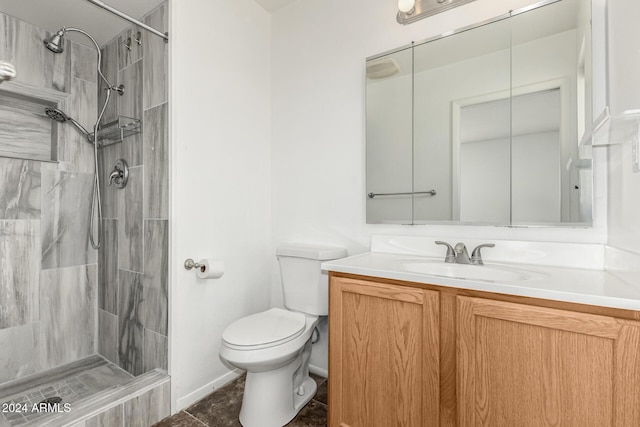 bathroom with a tile shower, vanity, toilet, and tile patterned floors