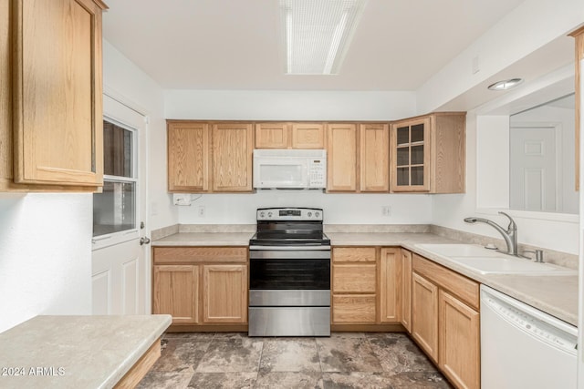 kitchen with light brown cabinets, white appliances, and sink