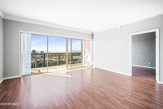 spare room with ornamental molding and wood finished floors