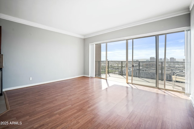 empty room with baseboards, a view of city, ornamental molding, and wood finished floors