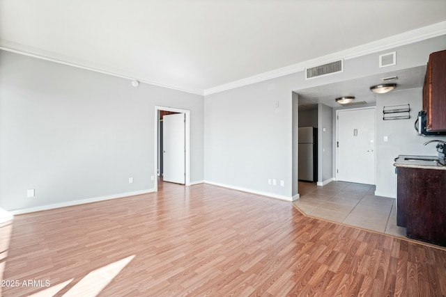 unfurnished living room featuring light wood-style floors, visible vents, crown molding, and baseboards