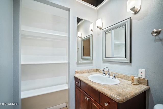 full bath featuring a textured wall and vanity