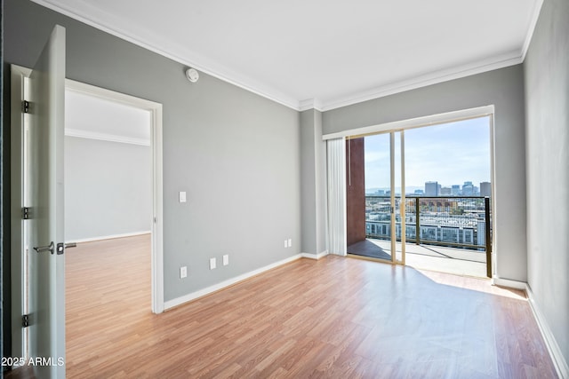spare room featuring a view of city, ornamental molding, wood finished floors, and baseboards