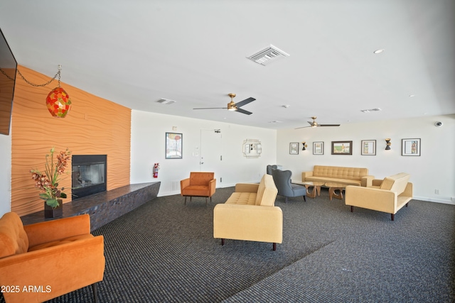 living area featuring carpet floors, a large fireplace, and visible vents