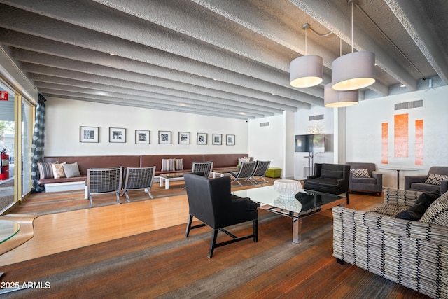 living area featuring beam ceiling, wood finished floors, and visible vents