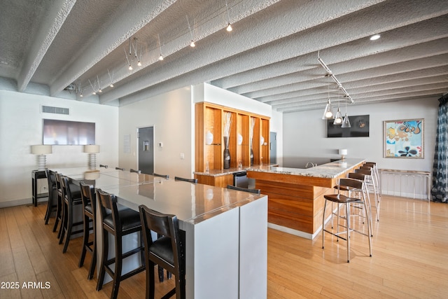 kitchen featuring light wood finished floors, a large island, and visible vents