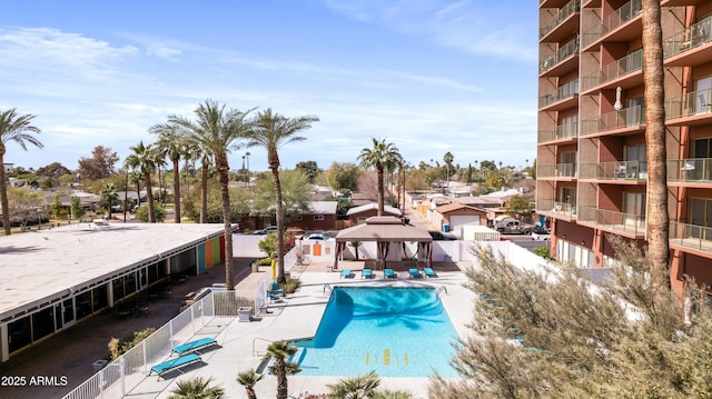 community pool with a patio area, fence, and a gazebo