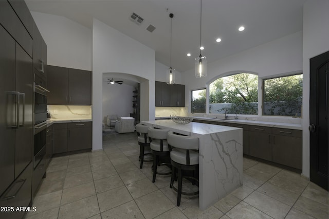 kitchen featuring a large island, decorative backsplash, pendant lighting, and light stone countertops