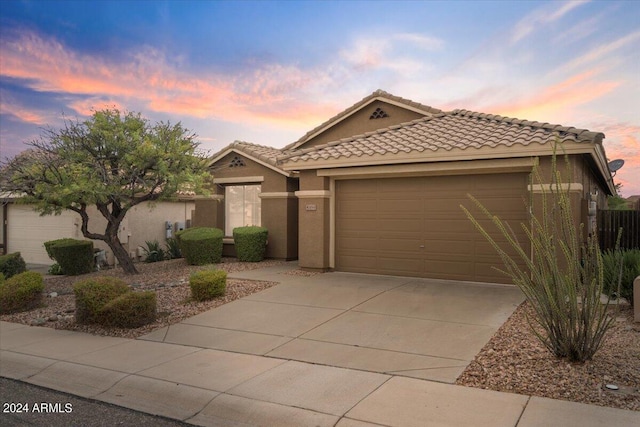 view of front facade with a tile roof, stucco siding, concrete driveway, and a garage