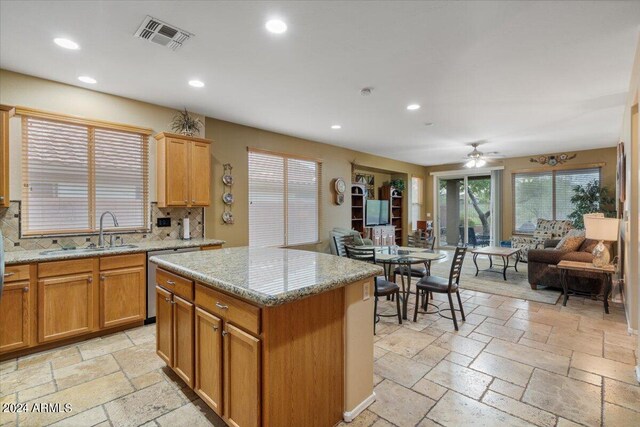 kitchen with tasteful backsplash, sink, a center island, and ceiling fan