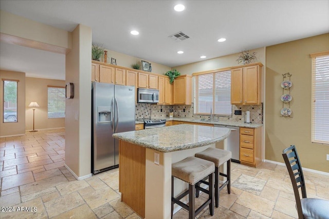 kitchen featuring appliances with stainless steel finishes, a wealth of natural light, and a center island