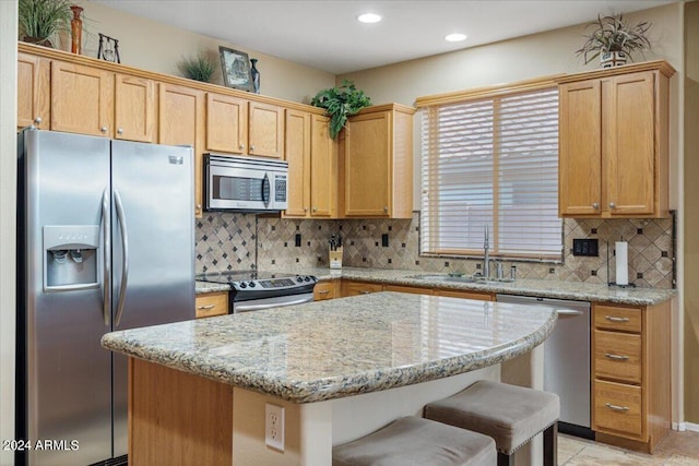 kitchen with backsplash, a breakfast bar, stainless steel appliances, sink, and light stone counters