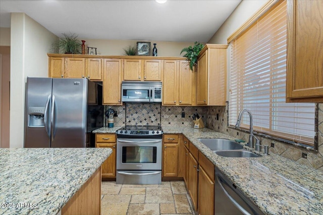 kitchen featuring appliances with stainless steel finishes, backsplash, light stone countertops, and sink