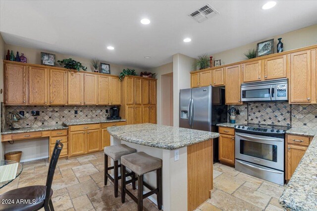 kitchen with light stone countertops, stainless steel appliances, and backsplash