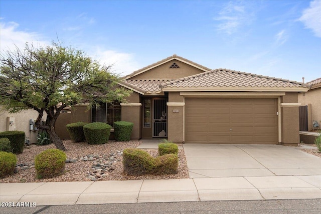 view of front facade with stucco siding, concrete driveway, an attached garage, and a tiled roof