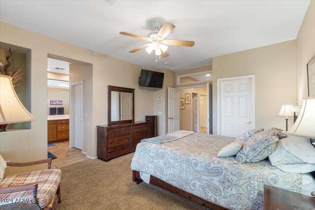 bedroom featuring ceiling fan, light colored carpet, and ensuite bathroom