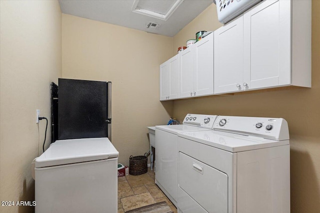 washroom featuring cabinets and washer and clothes dryer