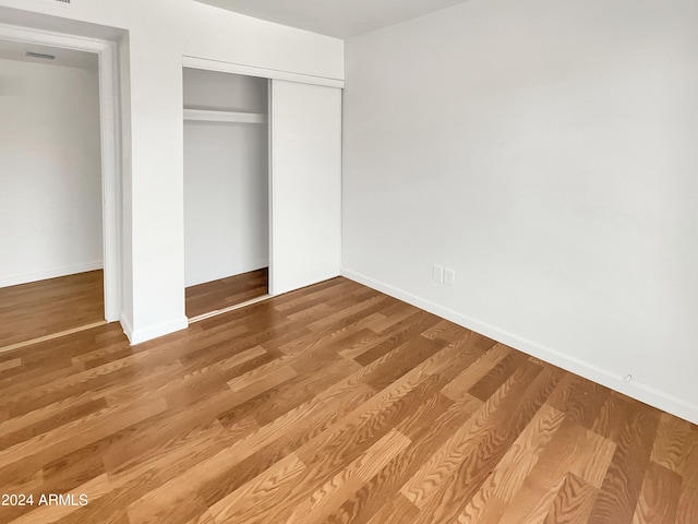 unfurnished bedroom with hardwood / wood-style floors and a closet