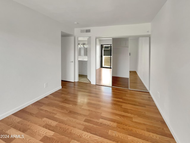 unfurnished bedroom with a closet, light hardwood / wood-style flooring, and ensuite bathroom