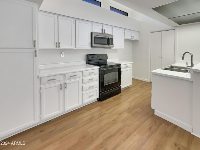 kitchen with black range with electric cooktop, light hardwood / wood-style floors, white cabinetry, and sink