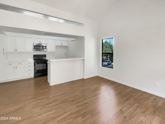 kitchen featuring white cabinetry, electric range, light hardwood / wood-style flooring, and vaulted ceiling