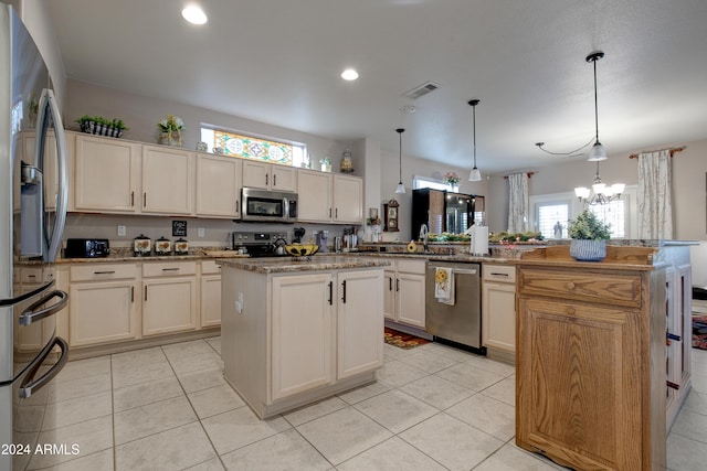 kitchen with kitchen peninsula, appliances with stainless steel finishes, pendant lighting, a chandelier, and a kitchen island