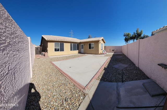 rear view of property featuring a patio, a fenced backyard, a tile roof, and stucco siding