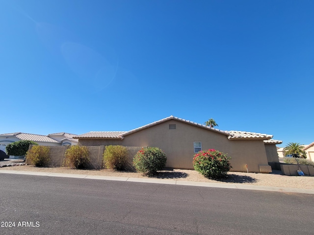 view of front facade featuring a tile roof, fence, and stucco siding