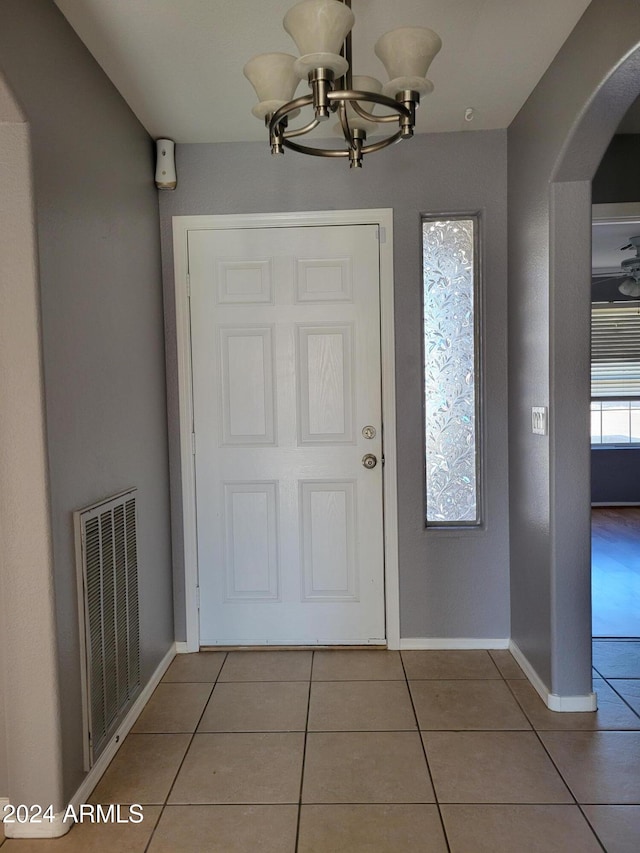 tiled foyer entrance featuring a chandelier