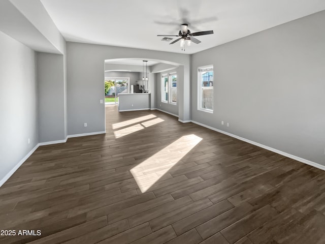 unfurnished living room featuring dark hardwood / wood-style flooring and ceiling fan with notable chandelier