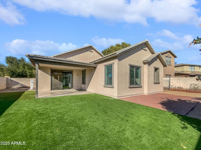 rear view of house featuring a lawn and a patio