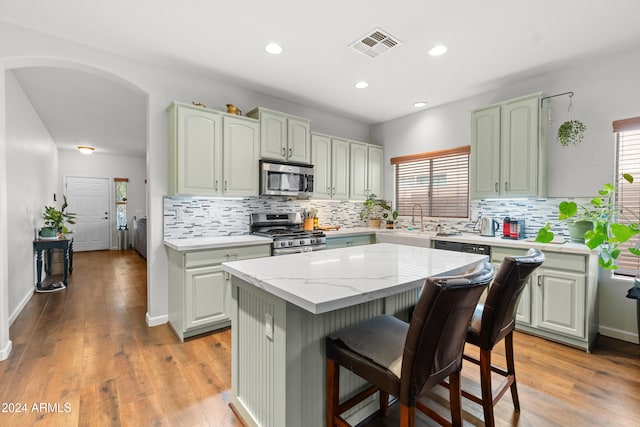 kitchen featuring light wood-type flooring, stainless steel appliances, a kitchen island, and a wealth of natural light