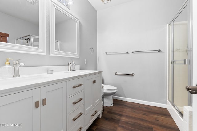 bathroom featuring hardwood / wood-style floors, vanity, toilet, and a shower with door