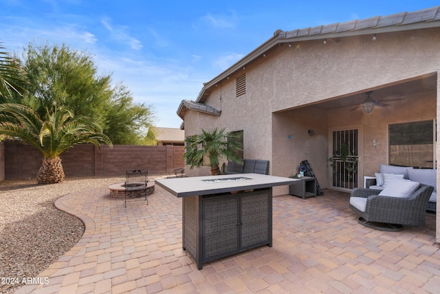 view of patio with ceiling fan and an outdoor living space with a fire pit