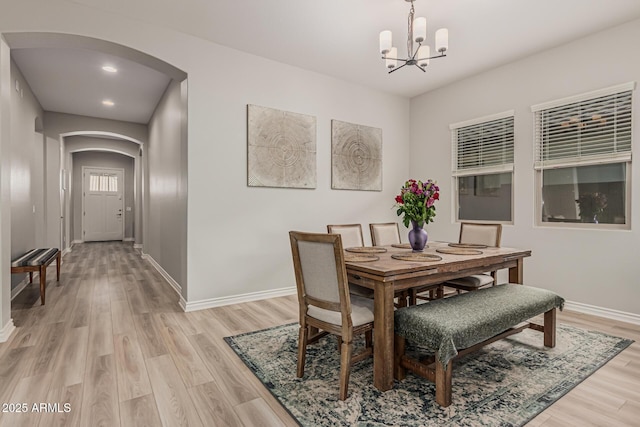 dining area featuring arched walkways, a chandelier, baseboards, light wood finished floors, and recessed lighting