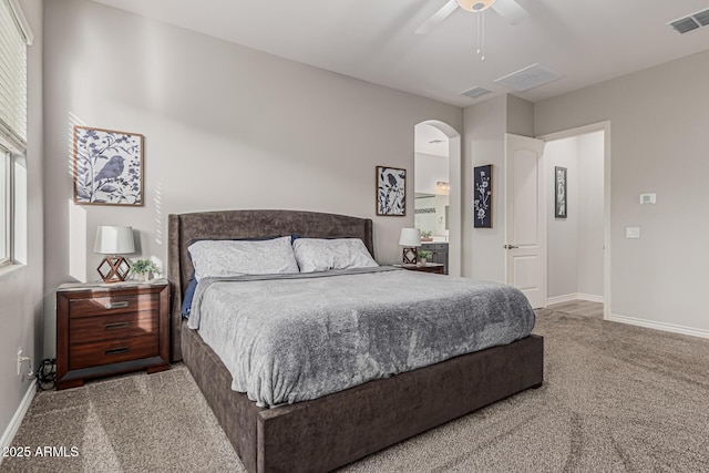 carpeted bedroom featuring baseboards, arched walkways, and a ceiling fan