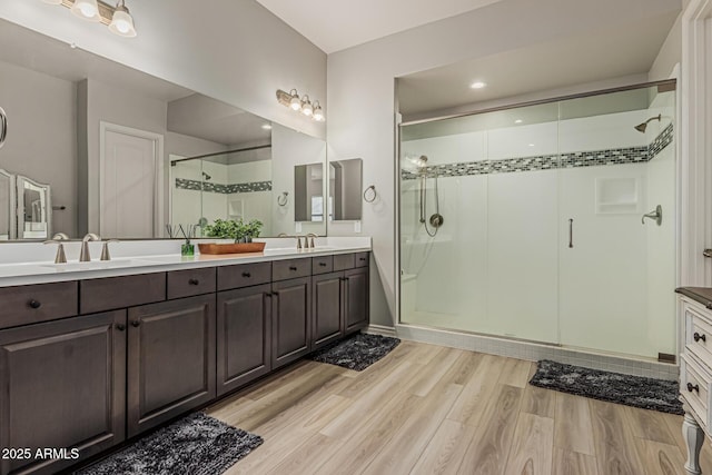 full bathroom featuring double vanity, a shower stall, wood finished floors, and recessed lighting