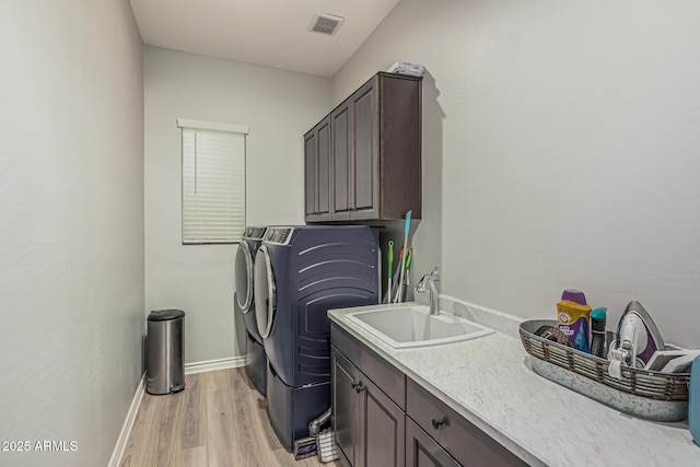 laundry room featuring cabinet space, separate washer and dryer, light wood-type flooring, and baseboards