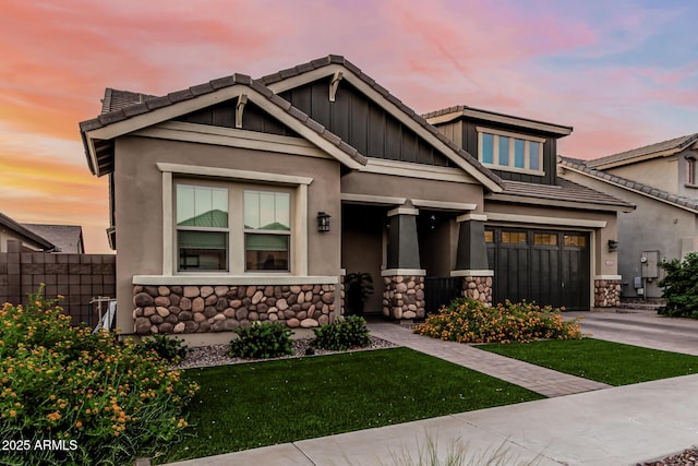 view of front of house with stone siding, driveway, a garage, and fence
