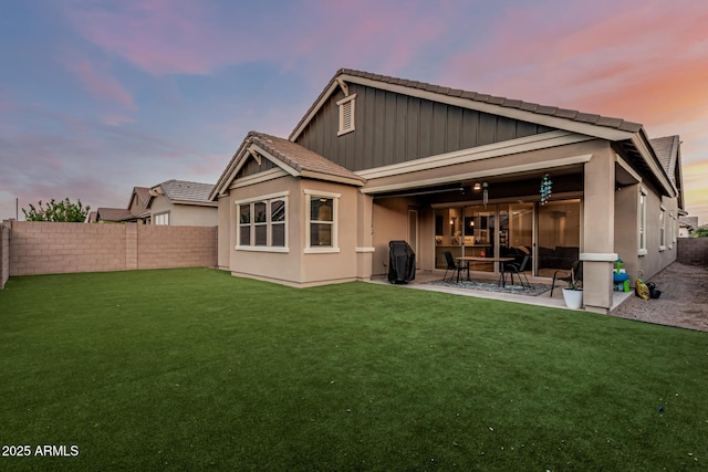 rear view of house with a patio, a tiled roof, board and batten siding, and stucco siding